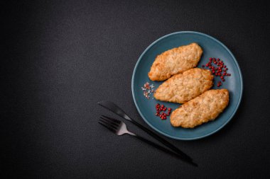 Lezzetli taze kızarmış balık ya da koyu beton arka planda baharat ve otlu tavuk pirzolası.