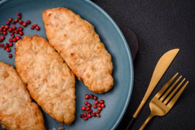 Lezzetli taze kızarmış balık ya da koyu beton arka planda baharat ve otlu tavuk pirzolası.