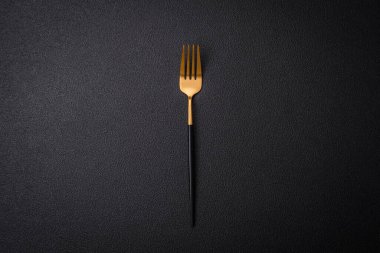 Koyu dokulu arka planda çelikten yapılmış mutfak çatalı. Mutfak aletleri masanın üstünde.