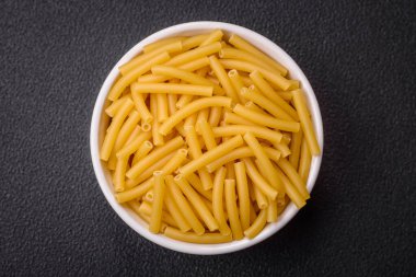 Koyu dokulu bir arka planda seramik tabakta tuzlu ve baharatlı tam tahıllı makarna.