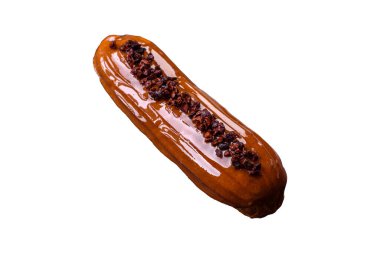 Delicious fresh eclair with chocolate cream on a black ceramic plate on a dark concrete background