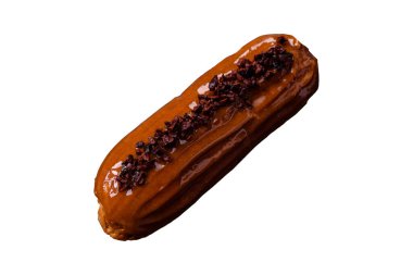 Delicious fresh eclair with chocolate cream on a black ceramic plate on a dark concrete background