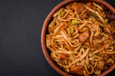 Sebzeli, mantarlı, tuzlu ve baharatlı lezzetli Asya udonu tabağı koyu beton arka planda.