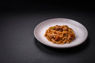 Sebzeli, mantarlı, tuzlu ve baharatlı lezzetli Asya udonu tabağı koyu beton arka planda.