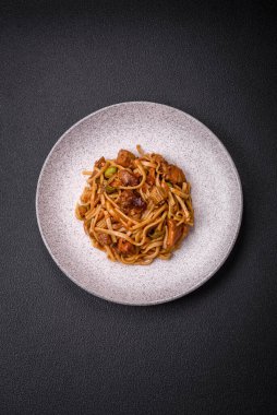 Sebzeli, mantarlı, tuzlu ve baharatlı lezzetli Asya udonu tabağı koyu beton arka planda.