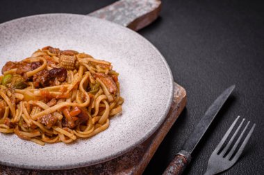Sebzeli, mantarlı, tuzlu ve baharatlı lezzetli Asya udonu tabağı koyu beton arka planda.