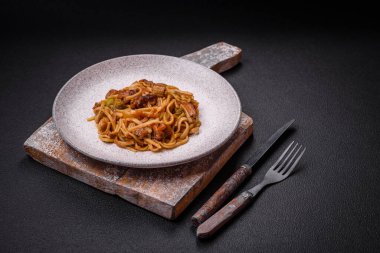 Sebzeli, mantarlı, tuzlu ve baharatlı lezzetli Asya udonu tabağı koyu beton arka planda.