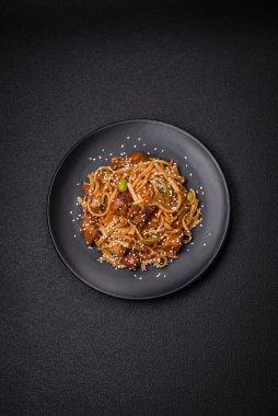 Sebzeli, mantarlı, tuzlu ve baharatlı lezzetli Asya udonu tabağı koyu beton arka planda.