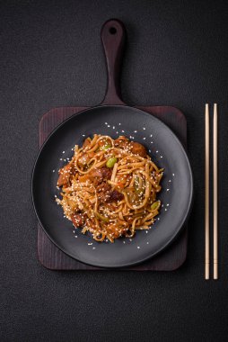 Sebzeli, mantarlı, tuzlu ve baharatlı lezzetli Asya udonu tabağı koyu beton arka planda.