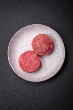 Koyu beton arka planda tuzlu ve baharatlı çiğ ton balıklı yuvarlak biftekler.