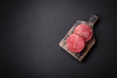 Koyu beton arka planda tuzlu ve baharatlı çiğ ton balıklı yuvarlak biftekler.