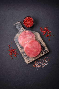 Koyu beton arka planda tuzlu ve baharatlı çiğ ton balıklı yuvarlak biftekler.