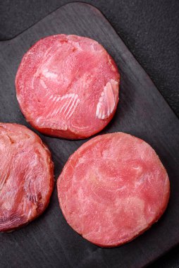 Koyu beton arka planda tuzlu ve baharatlı çiğ ton balıklı yuvarlak biftekler.