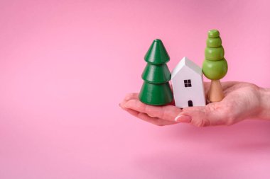 Kadın elleri, küçük ahşap bir ev ve anahtarlar kendi evinize yatırım yapmak ve gayrimenkul satın alma hedefine ulaşmak için. Fikrin için arka plan