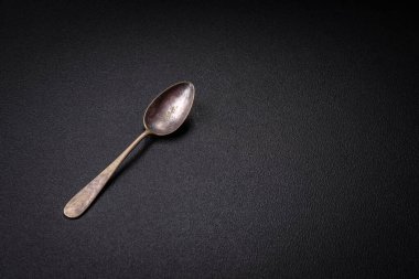 Empty metal spoon on dark textured concrete background. Cutlery, preparation for dinner