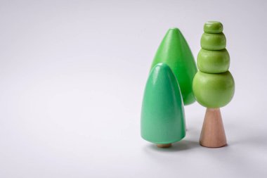 Beyaz arka planda yeşil taç ve gövdesi olan tahta bir ağaç modeli. Ahşap oyuncaklarla çocuk büyümesi