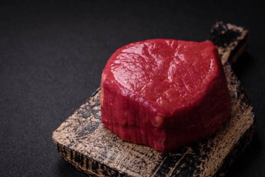 Taze taze çiğ fileminyon, arka planda tuz, baharat ve otlarla birlikte.