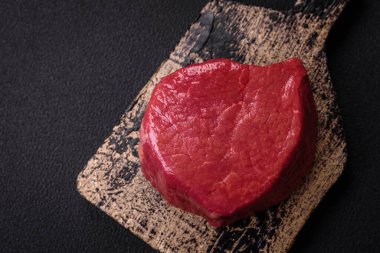 Taze taze çiğ fileminyon, arka planda tuz, baharat ve otlarla birlikte.