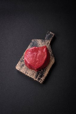 Taze taze çiğ fileminyon, arka planda tuz, baharat ve otlarla birlikte.