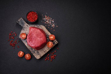 Taze taze çiğ fileminyon, arka planda tuz, baharat ve otlarla birlikte.