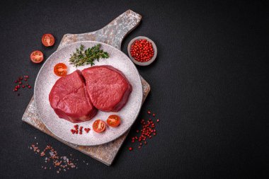 Taze taze çiğ fileminyon, arka planda tuz, baharat ve otlarla birlikte.