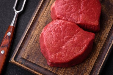 Taze taze çiğ fileminyon, arka planda tuz, baharat ve otlarla birlikte.