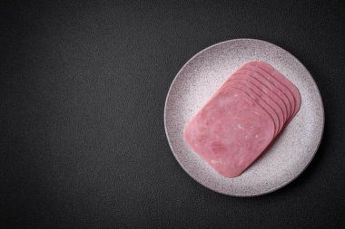 Lezzetli taze jambon, tuz, baharat ve otlarla dilimlenmiş koyu beton arka planda.