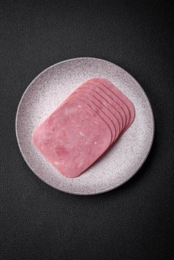 Lezzetli taze jambon, tuz, baharat ve otlarla dilimlenmiş koyu beton arka planda.