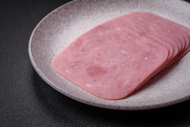 Lezzetli taze jambon, tuz, baharat ve otlarla dilimlenmiş koyu beton arka planda.