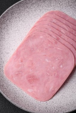 Lezzetli taze jambon, tuz, baharat ve otlarla dilimlenmiş koyu beton arka planda.