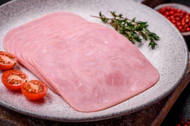 Lezzetli taze jambon, tuz, baharat ve otlarla dilimlenmiş koyu beton arka planda.