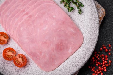 Lezzetli taze jambon, tuz, baharat ve otlarla dilimlenmiş koyu beton arka planda.