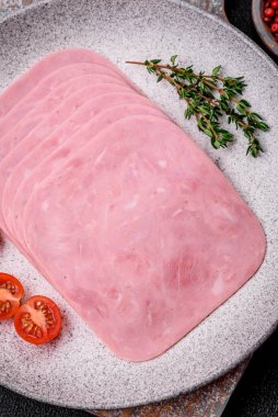 Lezzetli taze jambon, tuz, baharat ve otlarla dilimlenmiş koyu beton arka planda.