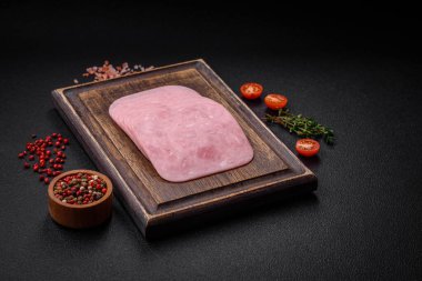 Lezzetli taze jambon, tuz, baharat ve otlarla dilimlenmiş koyu beton arka planda.