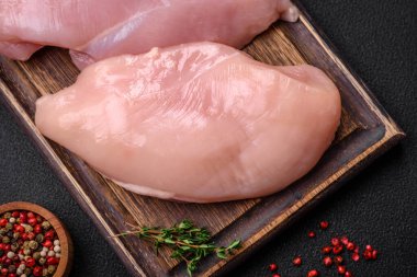 Koyu beton bir masada baharat ve otlarla taze tavuk filetosu. Et yemekleri için hazırlık.