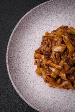 Sebzeli, mantarlı, tuzlu ve baharatlı lezzetli Asya udonu tabağı koyu beton arka planda.