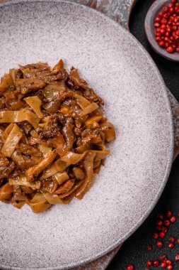 Sebzeli, mantarlı, tuzlu ve baharatlı lezzetli Asya udonu tabağı koyu beton arka planda.