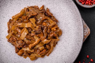 Sebzeli, mantarlı, tuzlu ve baharatlı lezzetli Asya udonu tabağı koyu beton arka planda.