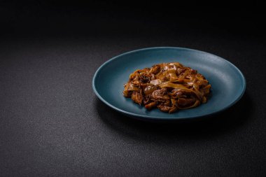 Sebzeli, mantarlı, tuzlu ve baharatlı lezzetli Asya udonu tabağı koyu beton arka planda.