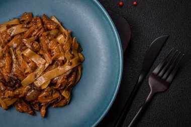 Sebzeli, mantarlı, tuzlu ve baharatlı lezzetli Asya udonu tabağı koyu beton arka planda.