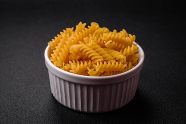 Koyu dokulu arka planda tam tahıllı buğday çeşitlerinden ham fusilli makarna.