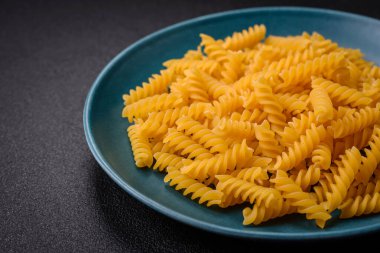 Koyu dokulu arka planda tam tahıllı buğday çeşitlerinden ham fusilli makarna.