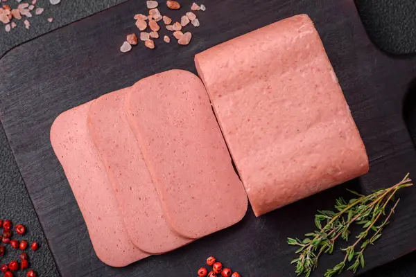 Stock image Delicious canned pink ham with salt, spices and herbs on a dark concrete background