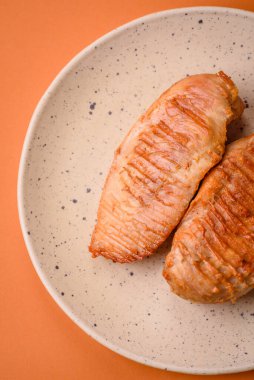 Lezzetli taze ızgara tavuk filetosu, esrarlı baharatlar ve çimento kaplı otlar. Ateşte pişirilmiş bir tabak.