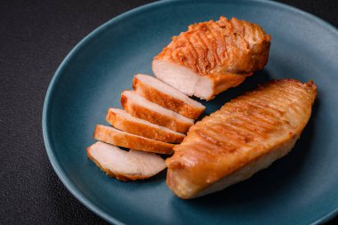 Lezzetli taze ızgara tavuk filetosu, esrarlı baharatlar ve çimento kaplı otlar. Ateşte pişirilmiş bir tabak.