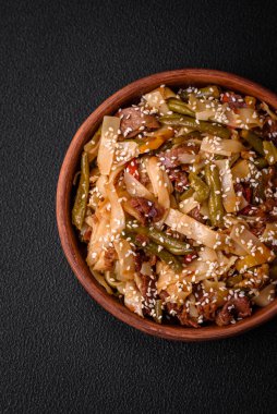 Lezzetli Asya yemeği udonu acı biber, yeşil fasulye, baharat ve otlar seramik tabakta koyu beton arka planda.