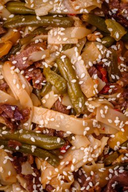 Lezzetli Asya yemeği udonu acı biber, yeşil fasulye, baharat ve otlar seramik tabakta koyu beton arka planda.