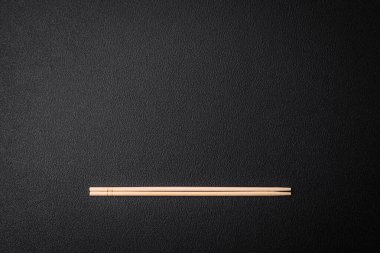 Boş bir arkaplanda, Asya yemekleri için bir zemin olarak açık tahta yemek çubukları. Boşluğu yiyecek gereçleriyle kopyala