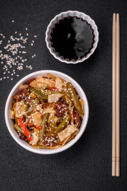 Lezzetli Asya yemeği udonu acı biber, yeşil fasulye, baharat ve otlar seramik tabakta koyu beton arka planda.