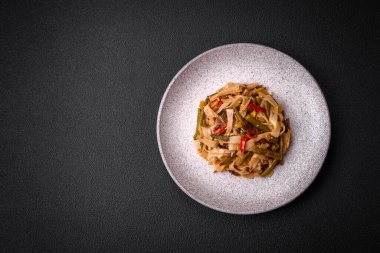 Lezzetli Asya yemeği udonu acı biber, yeşil fasulye, baharat ve otlar seramik tabakta koyu beton arka planda.